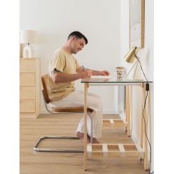 Hombre sentado escribiendo en mesa con patas de madera maciza y cintas cosidas a mano