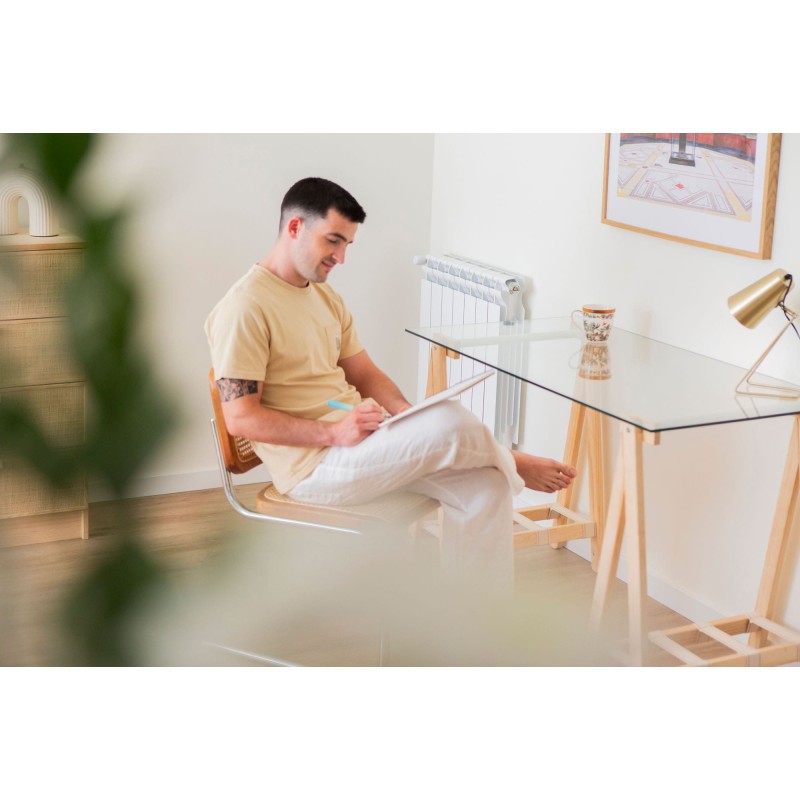 Hombre en zona de trabajo en casa con mesa de cristal y patas de madera