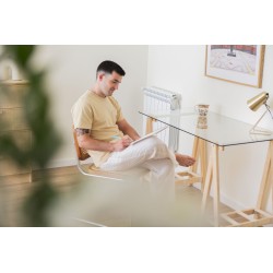 Hombre sentado disfrutando de la lectura junto a la mesa de madera y cristal